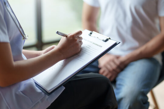Healthcare professional attentively writing down patient information during a consultation, providing personalized care.
