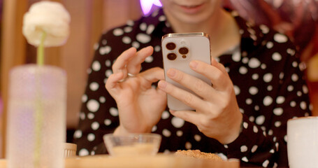 Close-up of a white smartphone with cameras in the hands of a cafe visitor is capturing moments of their dining experience to share on social media or document for personal memories, checking messages