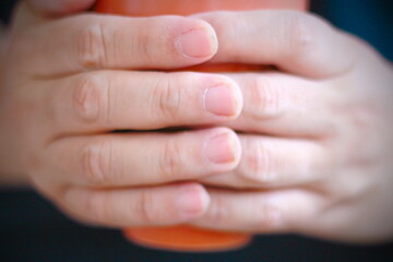 Man's hand holding a cup of coffee or tea, close up
