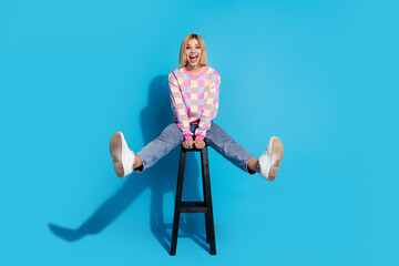 Full length photo of overjoyed eccentric girl wear pullover sit on bar chair astonished staring at...