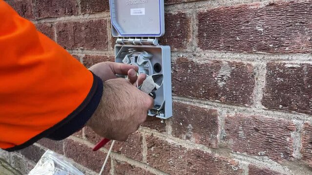 Engineer fixing full fibre optic cable broadband to a domestic home, England