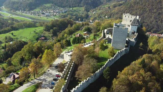 Drone footage of Celje Castle with fall trees, houses and mountain in Slovenia