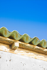 Old aged and damaged dangerous roof made of prefabricated and wave-shaped panels with wooden...