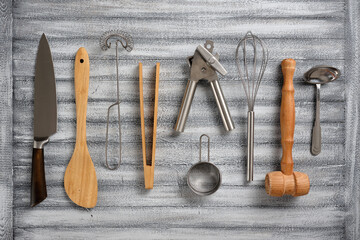 Many different kitchen utensils, wooden and metal, on a beautiful background.