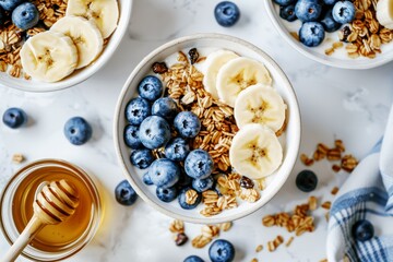 breakfast bowl with banana slices granola and blueberries, honey jar, white background, top view, closeup - Powered by Adobe