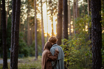 couple in love in the forest at sunset on a date hugging in a coat in the summer. Cinematic love story - Powered by Adobe