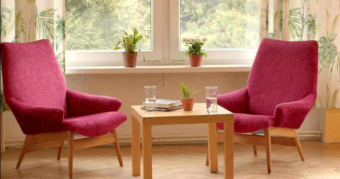 Two empty chairs in sunny office of psychotherapist. No people. Bright, welcoming space for therapy sessions. Calm and tranquility, peaceful environment conducive to introspection and healing. 