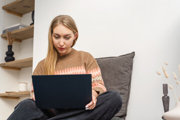Young woman using laptop in cozy living room.