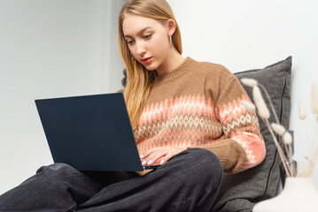 Young woman using laptop in cozy living room.