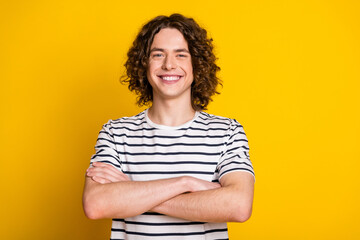 Photo of nice young man folded arms empty space wear striped t-shirt isolated on yellow color...