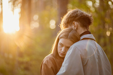 couple in love in the forest at sunset on a date hugging in a coat in the summer. Cinematic love...