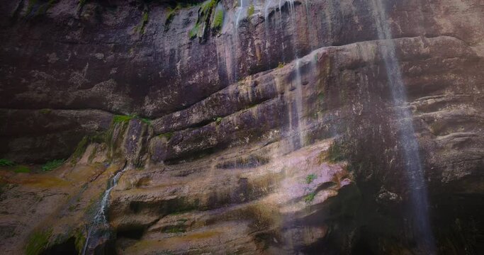Chegem waterfalls. An amazing stream of water flows like a waterfall from a stone wall directly into a stormy river. Russia. Caucasus. Kabardino-Balkarian Republic.