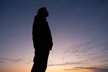 Low angle shot of a silhouette of a male under a sunset sky