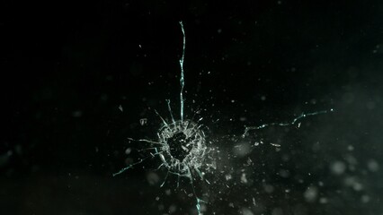 Close-up of gunshot through the glass, shattering against the black background