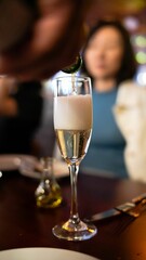 Hand pouring a Champaign on a glass with a blurred woman background