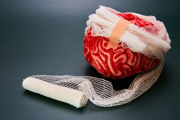 Concept of diseased brain depicted with a bandaged brain with a dark background.