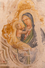 Close-up on medieval fresco in ruins on wall showing Virgin Mary dressed in blue with baby Jesus happy in her arms