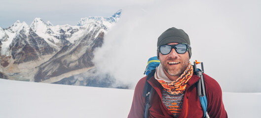 Cheerful laughing climber in sunglasses portrait with backpack ascending Mera peak high slopes at...
