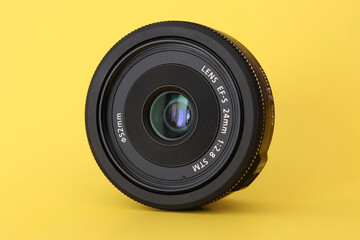 DSLR camera lens - digital camera lens 24 mm prime lens with yellow blurred background