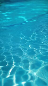 Close view of clear beautiful blue flowing water in swimming pool. Slow motion vertical video. Water surface. Travel and vacation concept. Summer