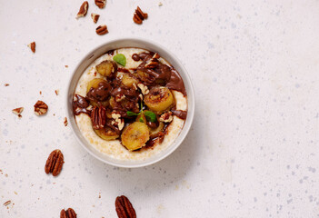 Oatmeal with caramel bananas and chocolate in to the bowl - 776042828