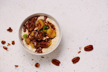 Oatmeal with caramel bananas and chocolate in to the bowl - 776042845