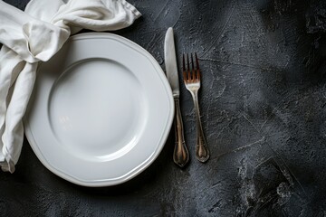 A white porcelain plate with a fork and knife placed neatly on top, part of a complete table setting with utensils and napkins