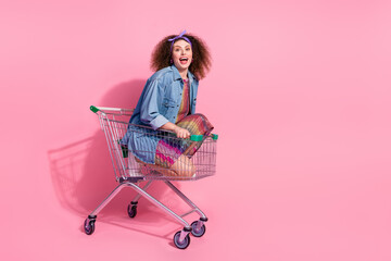 Full length photo of impressed funky lady dressed denim outfit riding shopping cart empty space...