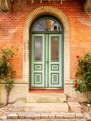 Front view of green door with roses in old town of Mariager, Nordjylland, Denmark