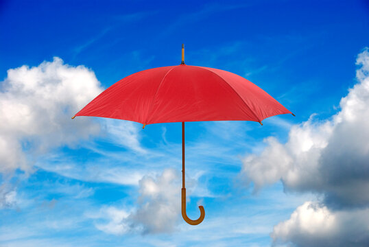 red umbrella over a blue sky with white clouds