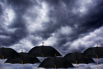 open black umbrellas under a dramatic cloudy and stormy sky