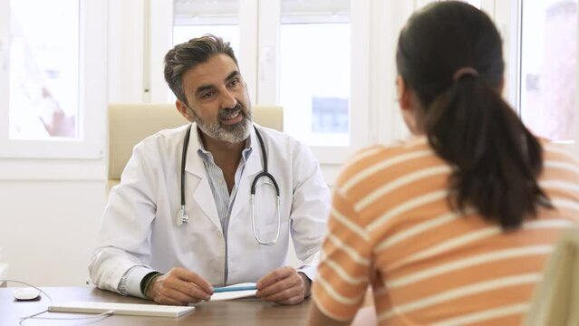 Confident male doctor talking to patient in clinic during daytime