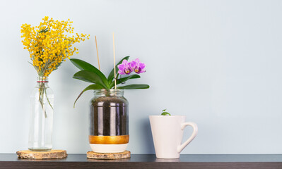 Decoration with yellow mimosa flowers and orchids on shelf on grey background. Copy space.