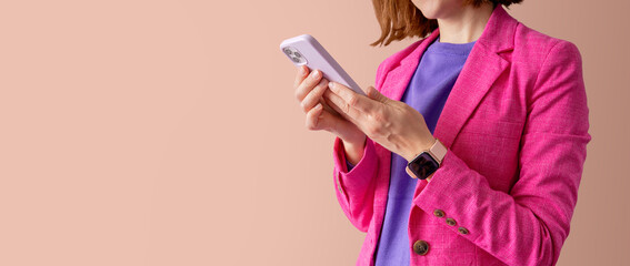 Woman wearing bright clorful business wear and typing message on phone against orange  background