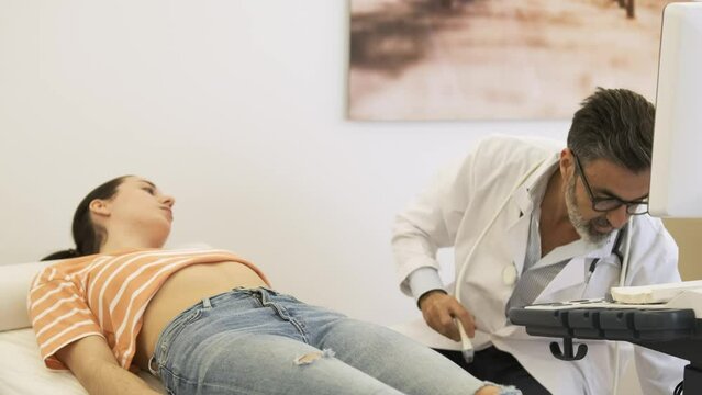 Sonographer doing abdomen ultrasound examination of woman in hospital