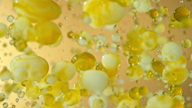 Super Slow Motion Shot of Moving Oil and Milk Bubbles on Golden Background, Cosmetics Concept, Filmed on High Speed Cinematic Camera at 1000fps.