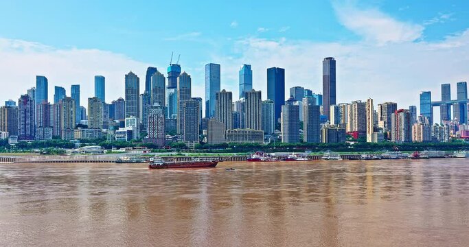 Modern city buildings skyline and river with moving boats in Chongqing