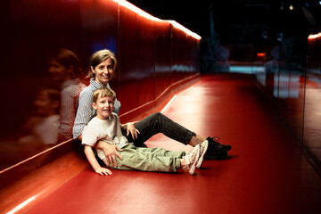 Woman and Little Boy Share Genuine Smiles Against Red Background, Radiant Joy.