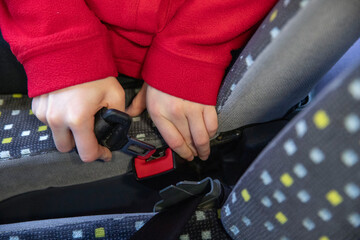 Gros plan d'un enfant attachant sa ceinture de sécurité dans un bus