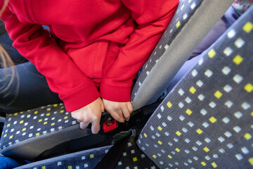 Gros plan d'un enfant attachant sa ceinture de sécurité dans un bus - obrazy, fototapety, plakaty