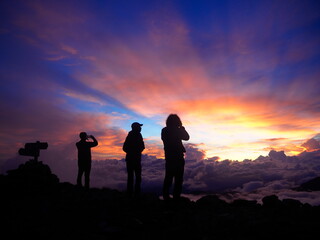 雲海に沈む夕日に見惚れる登山者たち