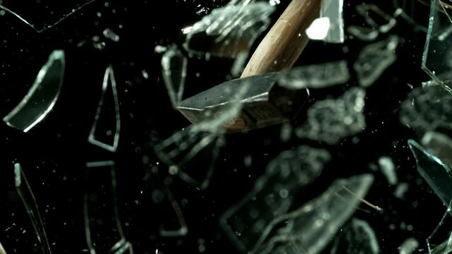 Super slow motion of glass-breaking hammer, shattering against black background . Filmed on high speed cinema camera, 1000 fps .