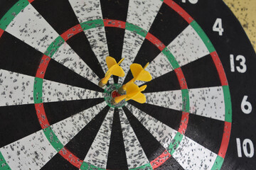 Three Yellow Darts Targetted in the Center of a Dartboard