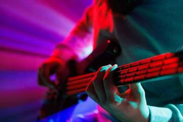 Detailed photo, cropped portrait of of musician strumming guitar strings, illuminated by intense...