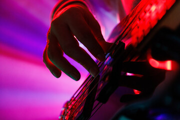 Close up photo of musician's hand on guitar neck with blue backlight and hazy smoke, highlighting musical performance. Concept of rock and classic music, hobby and work, energy, music festivals. Ad