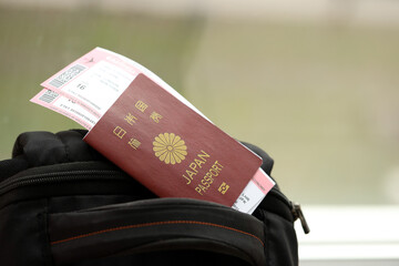 Japan passport with airline tickets on touristic backpack close up. Tourism and travel concept