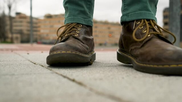 A man in brown leather boots walks down the street and steps in dog poop. Some owners have not picked up their pet's droppings. Bad luck or good luck, depending on how you look at it.