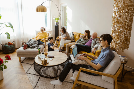 Multi-generation family spending leisure time while sitting in living room at home