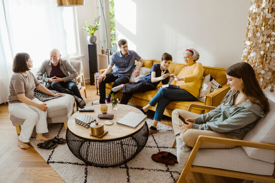 Multi-generation family using wireless technologies and talking while sitting in living room at home