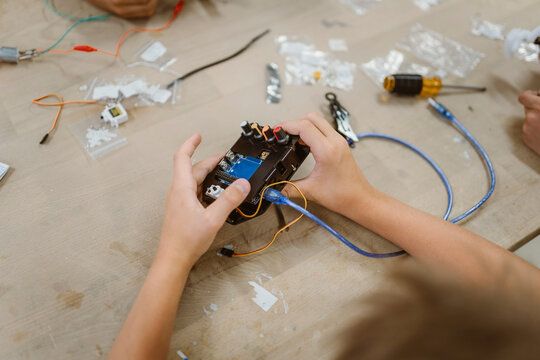High angle view of student examining electrical component on table at school workshop